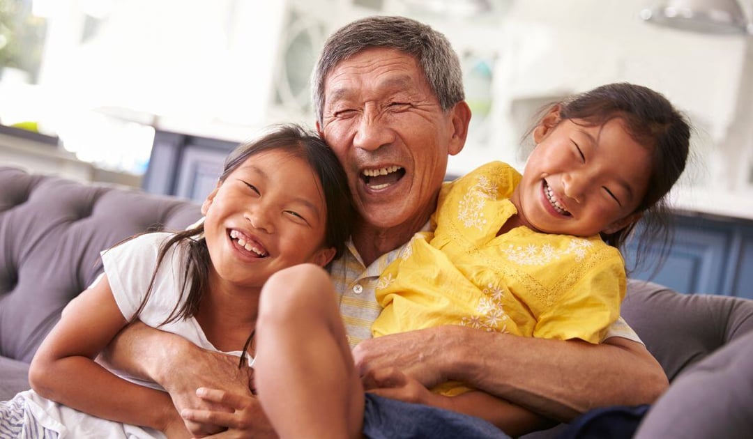 Older Asian man playing with his grandchildren at home