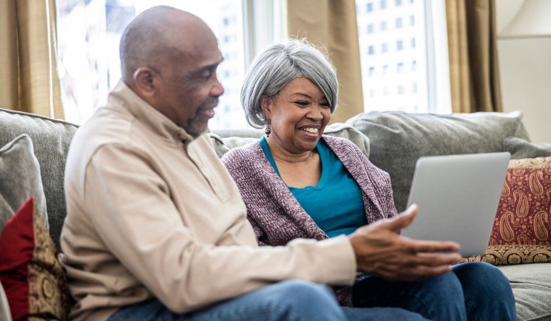 Older black couple on the couch with a laptop computer