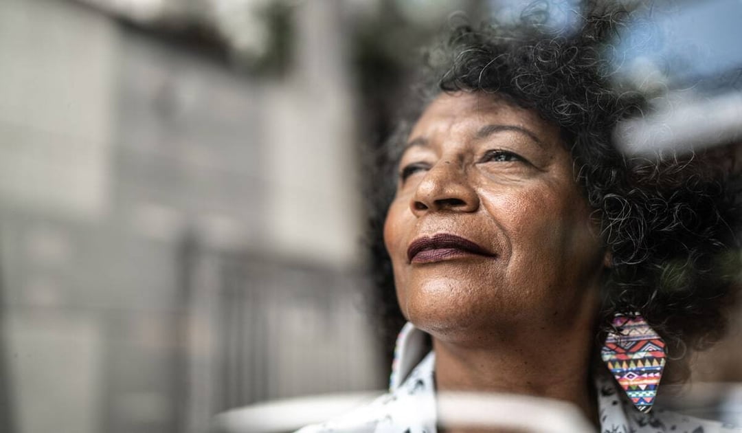 Older black woman looking out of a window