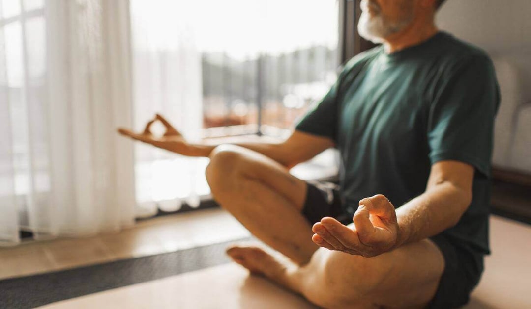 Older white man practicing yoga at home