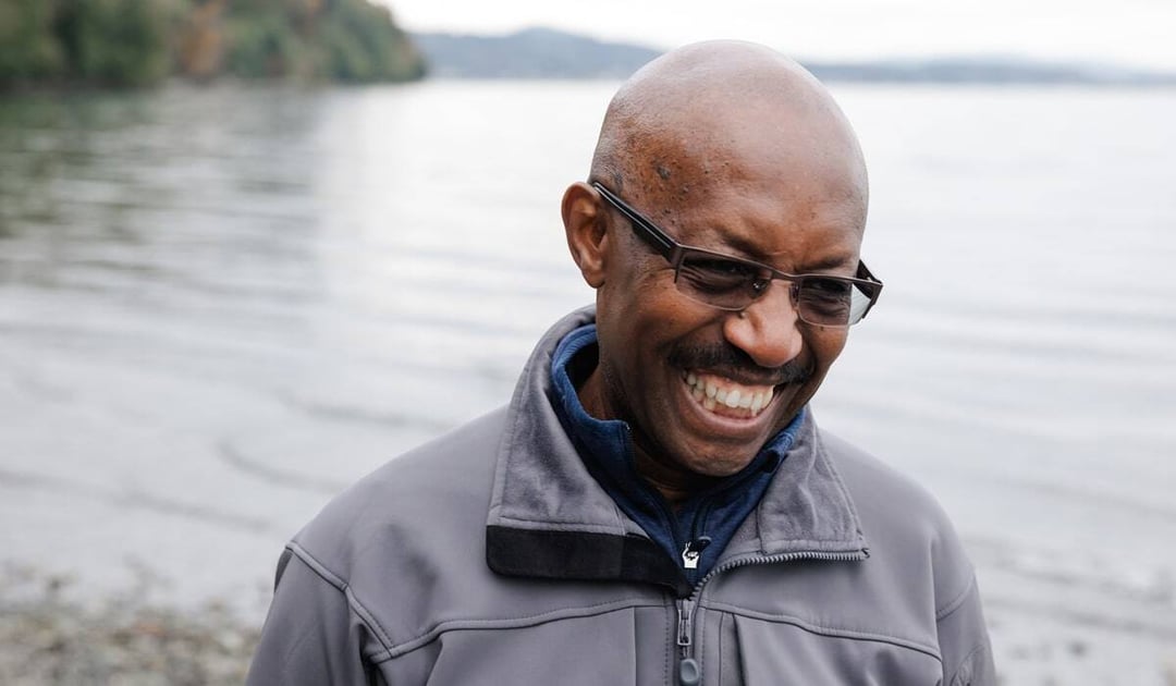 Older black man smiling near the ocean