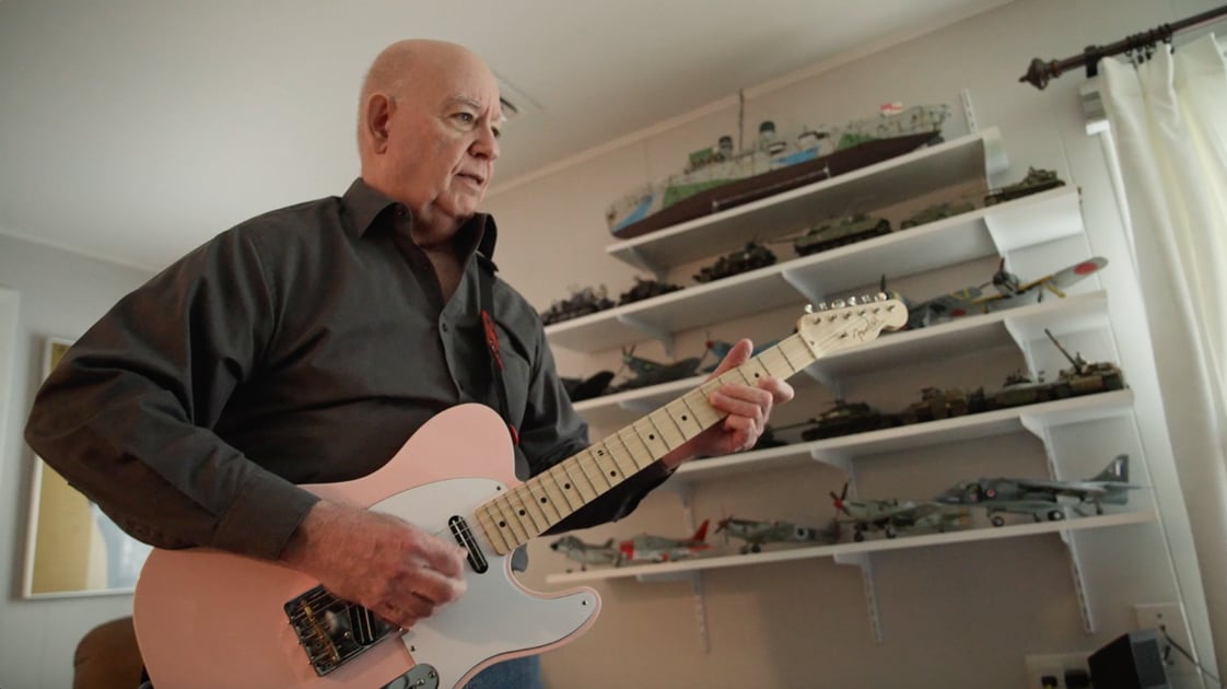 White man playing the guitar at home