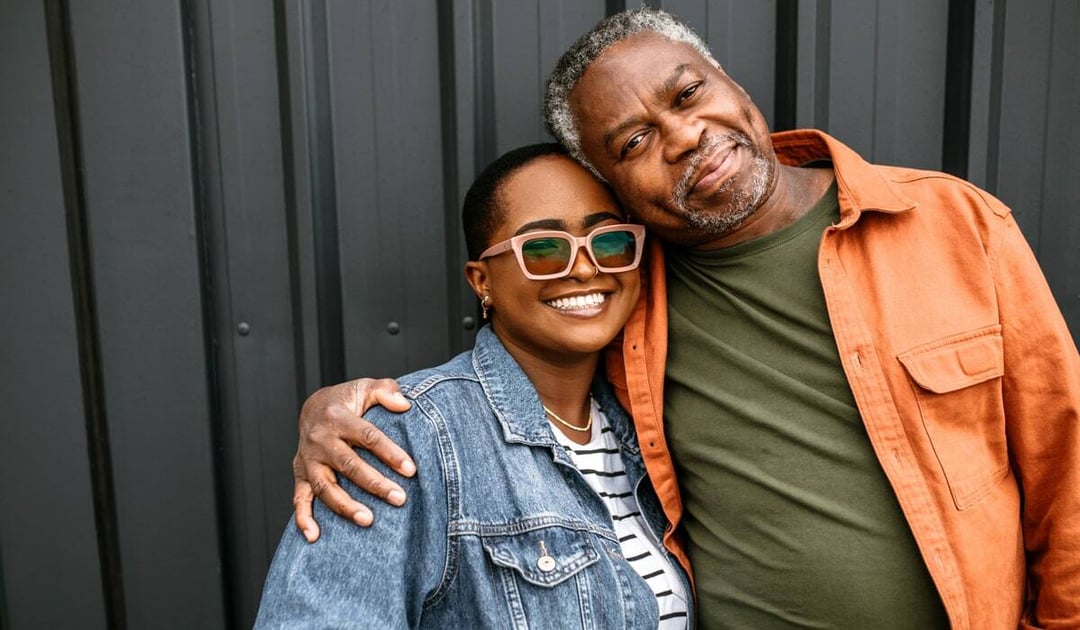 Older black man embracing adult daughter