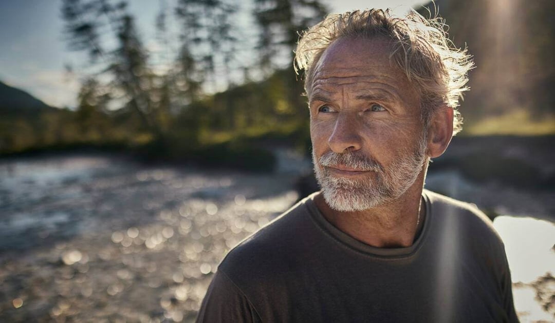 Older white man looking into the distance on the beach