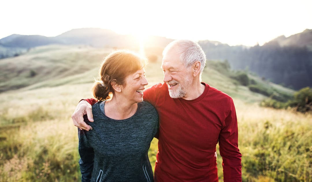 Older couple walking on a sunny hillside