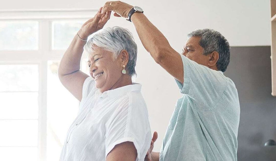 Older Latino couple dancing in their kitchen,