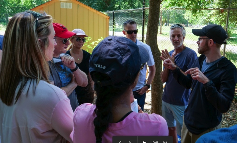 A group of men and women outside having a discussion